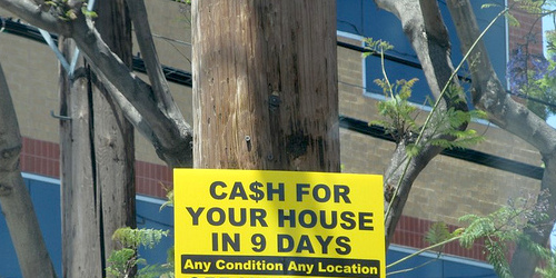 A sign on a utility pole reads: Cash for your house in 9 days. Any condition, any location.